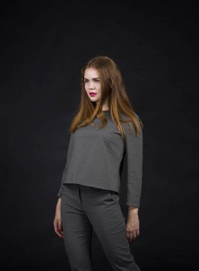 Kızıl saçlı kız pantolon takım uzun saçlı. Karanlık bir arka plan üzerinde stüdyoda poz.