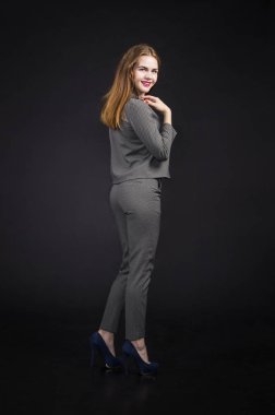 Kızıl saçlı kız pantolon takım uzun saçlı. Karanlık bir arka plan üzerinde stüdyoda poz.