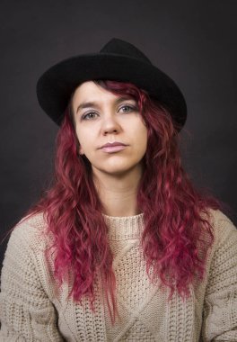 Bir şapka ve koyu bir arka plan Studio.Isolated görüntülerde poz uzun saçlı kazak duygusal esmer.