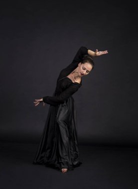 Genç kız siyahlı gülümseyen bir dans eden modern koreografi uygun. Stüdyo koyu arka plan üzerinde izole görüntü vurdu.