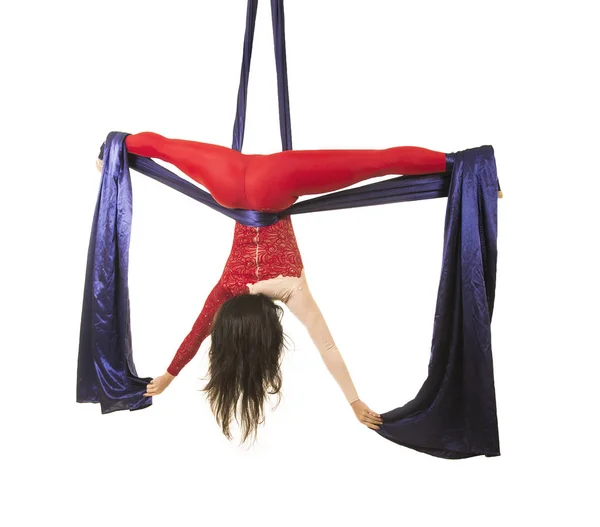 Молодая девушка с длинными волосами в красном костюме выполняет гимнастические и цирковые упражнения на шелке . — стоковое фото