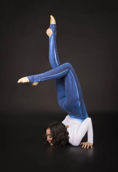 Acrobata ragazza, ginnastica, un giovane atleta in abito blu e bianco, praticare acrobazie . — Foto Stock