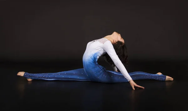 Menina acrobata, ginástica, um jovem atleta de terno azul e branco, praticando acrobacias . — Fotografia de Stock