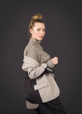 Açık ceketli ve koyu renk renkte poz veren bir kız..