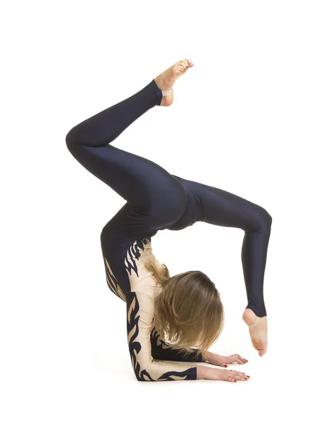 Girl gymnast, in a blue and white suit, engaged in acrobatics. Stock Photo