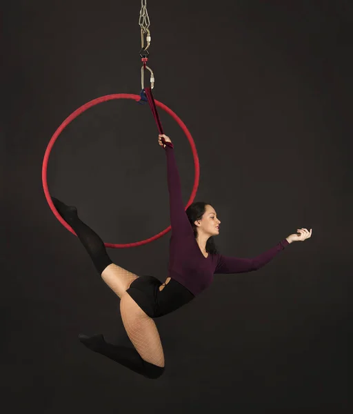 Una chica en un traje oscuro y polainas realiza elementos acrobáticos en el anillo de aire . — Foto de Stock