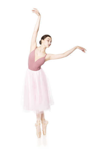 Elegant girl in a pink skirt and beige top dancing ballet.