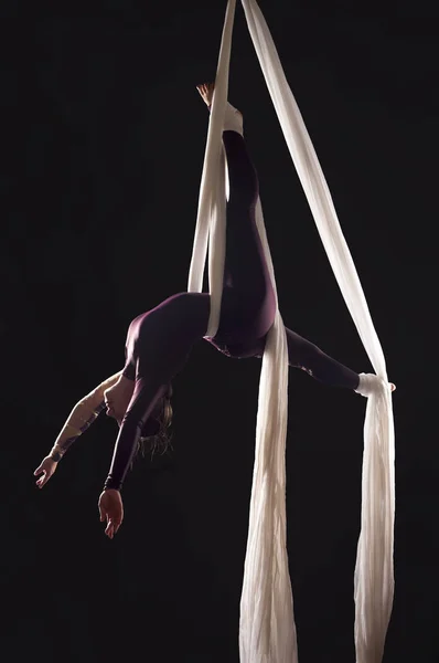 Αθλητικό κορίτσι σε ένα Μπορντώ κοστούμι εκτελεί ασκήσεις γυμναστικής και τσίρκου σε λευκό μετάξι, στο φανάρι. — Φωτογραφία Αρχείου