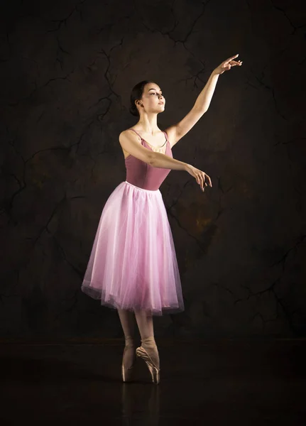 Uma menina esbelta em uma saia rosa e bege top dança balé . — Fotografia de Stock