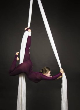 Bir Burgundy takım elbise sportif kız beyaz ipek üzerinde jimnastik ve sirk egzersizleri gerçekleştirir.