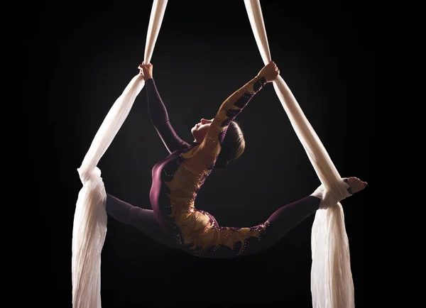 Chica deportiva en un traje de Borgoña realiza ejercicios de gimnasia y circo en seda blanca, en la luz de la contra . — Foto de Stock