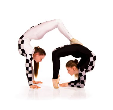 İki genç kadın denge beyaz arka planda akrobatik elementler sergiliyor. Stüdyo çekimi.