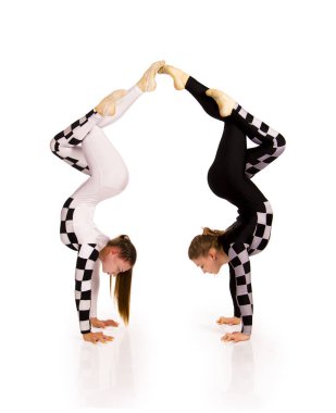 İki genç kadın denge beyaz arka planda akrobatik elementler sergiliyor. Stüdyo çekimi.