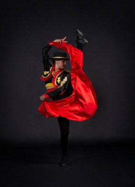 Boğa güreşçisi olarak stilize edilmiş bir sahne kostümüyle zarif bir şekilde dans eden plastik kız. Karanlık bir arkaplanda stüdyo çekimi.