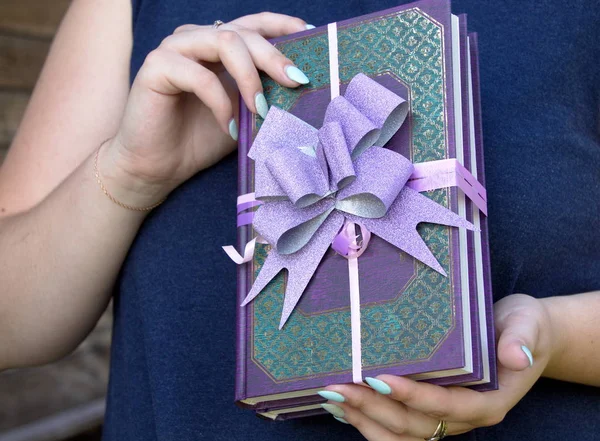 books as a gift decorated with a bow holding women\'s hands