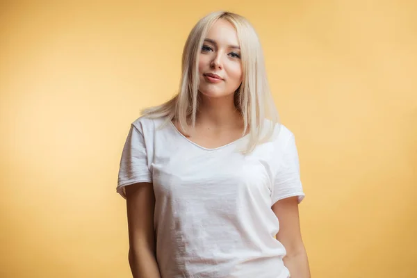 Retrato de cerca de una hermosa rubia en una camiseta blanca . — Foto de Stock