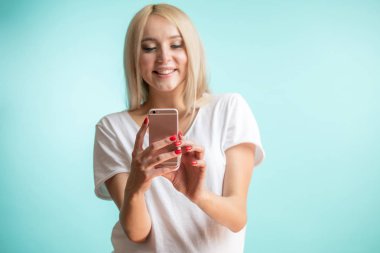 Onun smartphone üzerinde mavi arka plan kullanarak güzel sarışın modeli.