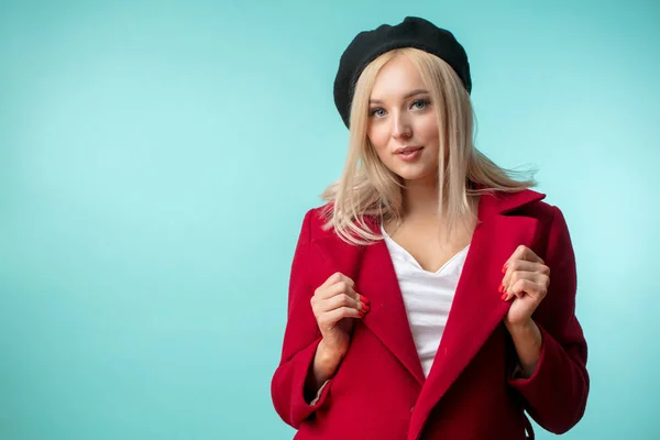 Gut aussehende blonde Frau mit rotem Mantel und schwarzer Baskenmütze — Stockfoto