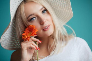 Portakal çiçeği tutan şapkalı çekici genç kadın portresi