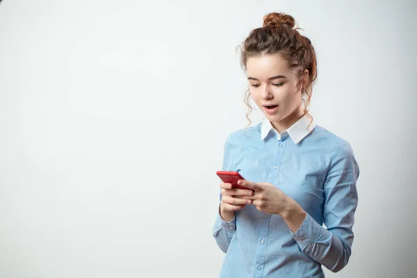 Agradable chica con la boca abierta lectura de información impactante por el teléfono inteligente — Foto de Stock