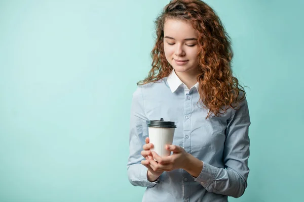 Крупным планом портрет имбирной девушки, держащей в руках и смотрящей на кофе — стоковое фото