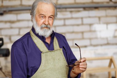 eski gri saçlı joiner mavi gömlek ve çalışırken kamera için poz önlük