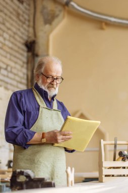 yakın çekim yan alıştırma kitabı onun çalışma içinde tutan ihtiyar bir adamın fotoğrafını göster
