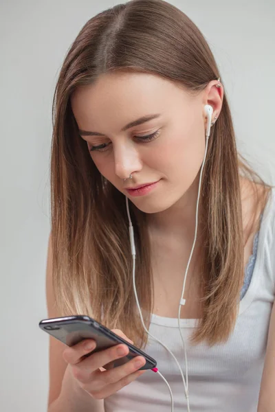 Junge angenehme Frau surft im Netz, während sie Musik hört — Stockfoto