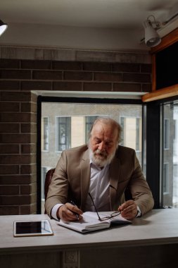 karanlık odada işyerinde masada oturan kapalı gözler yorgun yaşlı adamla. yorgunluk kavramı. zaman içinde çalışma