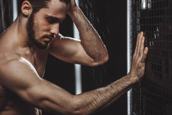 Chico guapo desnuda se apoya en la pared y tener una ducha fría . — Foto de Stock