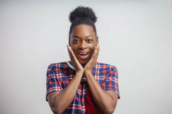 Erstaunen über gute Nachrichten. Emotionale junge schwarze Frau mit den Händen auf den Wangen — Stockfoto