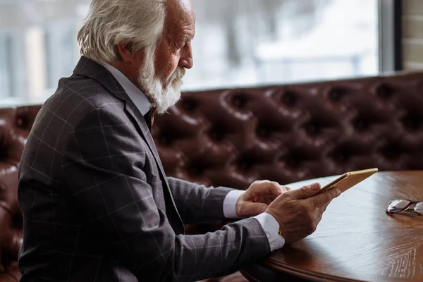 Seitenansicht eines alten Mannes auf der Suche nach Informationen vom Tablet — Stockfoto