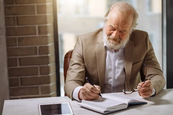 Knappe man van de oude opname van zijn observationsin een notebook — Stockfoto