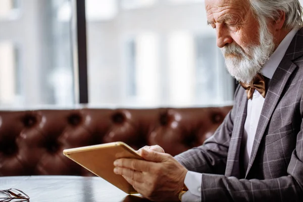 Крупный план обрезанный вид сбоку снимок старого красивого мужчины, читающего электронную книгу — стоковое фото