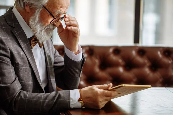 Hombre de pelo gris en gafas usando iPad en casa —  Fotos de Stock