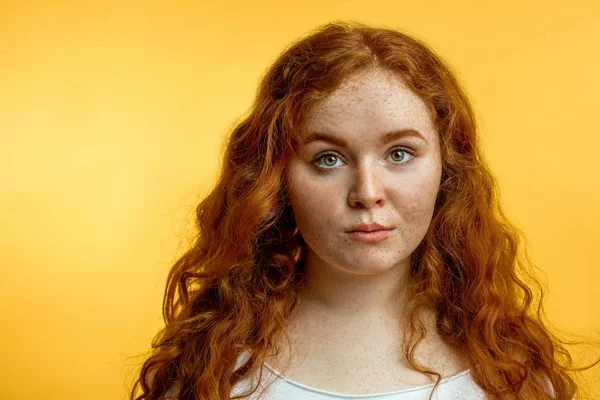 Niedliche fröhliche rothaarige junge Mädchen in gelbem T-Shirt über blauem Hintergrund mit lustigem Gesicht. — Stockfoto