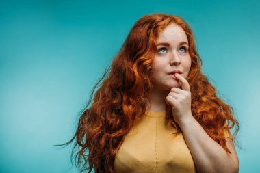 Sarı t-shirt komik surat ile mavi arka plan üzerine şirin neşeli Kızıl saçlı Genç kız.