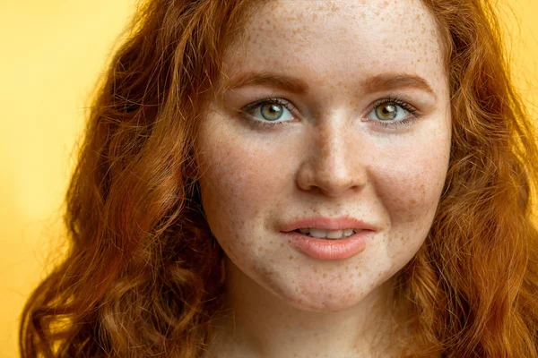 Close-up of beautiful red-haired freckled girl with loose curly hair