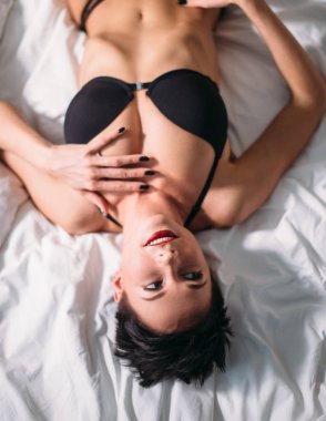 Pahalı dantelli iç çamaşırlarıyla yatakta yatan güzel esmer manken.