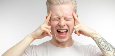 Bitcoin fiyatlarındaki ani düşüşten bıkmış, parmaklarını şakaklarda tutan adam.