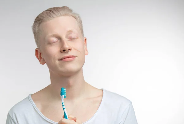 Hombre con los ojos cerrados sosteniendo el cepillo de dientes en la mano. Cuidado dental y salud dental — Foto de Stock