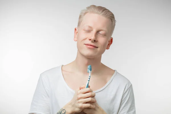 Férfi csukott szemmel tartja a kezében a fogkefe. Fogászati ellátás, és a fogak egészségének — Stock Fotó