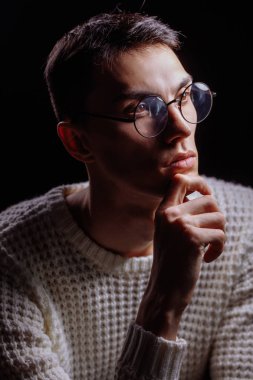 Beyaz süveter ve güneş gözlüğü takan yakışıklı bir erkek modelin stüdyo fotoğrafı.