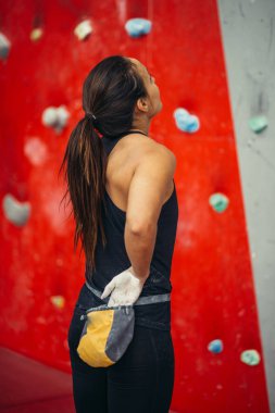 Dikiz manzaralı dağcı kadın, belindeki torbadan çıkan tebeşir tozuyla ellerini ovuşturuyor..