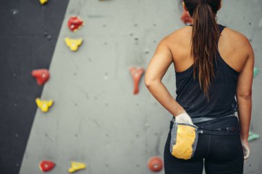 Dikiz manzaralı dağcı kadın, belindeki torbadan çıkan tebeşir tozuyla ellerini ovuşturuyor..