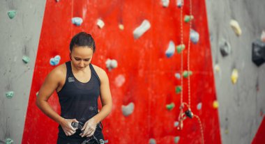 Dağcı uygun koşum takımı kapalı kayalıklarda tırmanmaya hazırlanıyor.