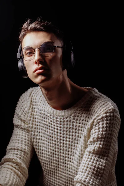 Beyaz tişört ve güneş gözlüğü takan yakışıklı bir erkek mankenin stüdyo fotoğrafı.