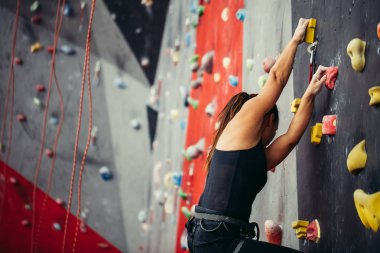 Renkli bir tırmanış salonunda spor yapan genç bir kadın..