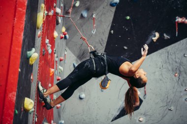Active happy woman overhanging on tightrope in the training climbing center clipart