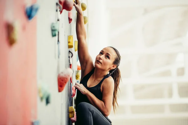 Fit vrouw bij de rots klimwand in de sportschool — Stockfoto